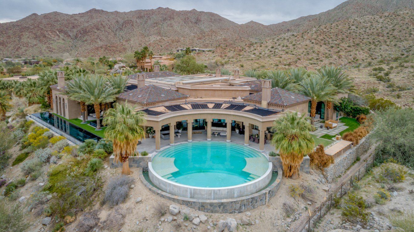 Desert hillside luxury home with a turquoise pool and mountain backdrop