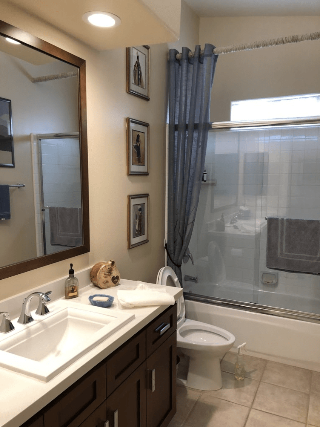 Modern bathroom with double vanity, large mirror, tub-shower, gray curtain, and tiled floor