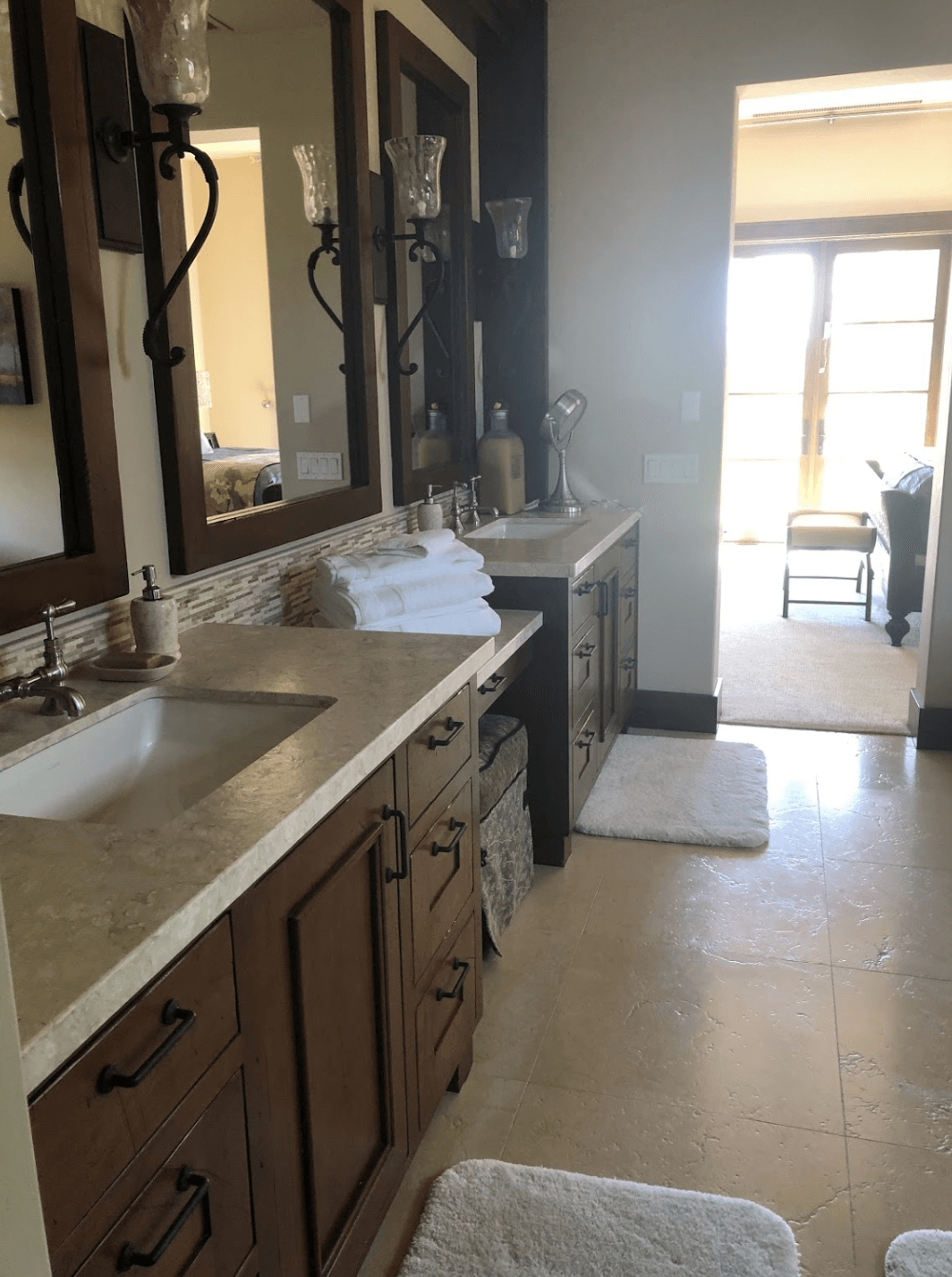 Narrow kitchen with sink, stove, and mirror, leading to a bright dining area.