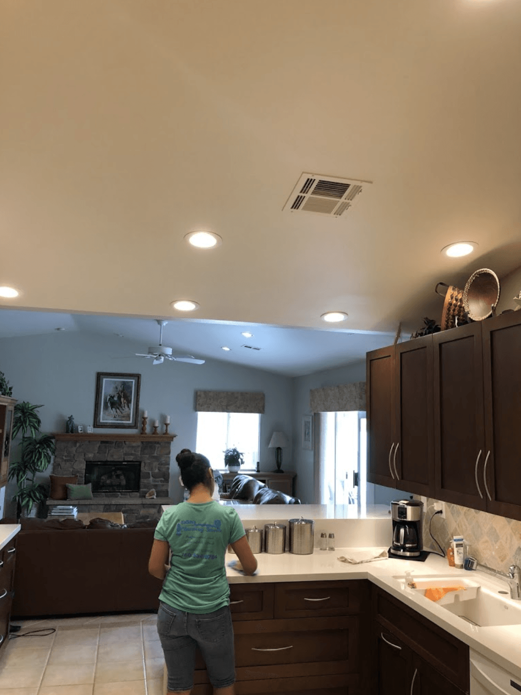 Woman standing at a kitchen counter in a bright, modern kitchen with dark wood cabinets