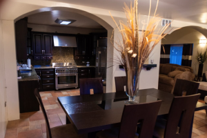 Dining room and kitchen with dark wood table, black cabinets, tiled floor, and decorative vase centerpiece